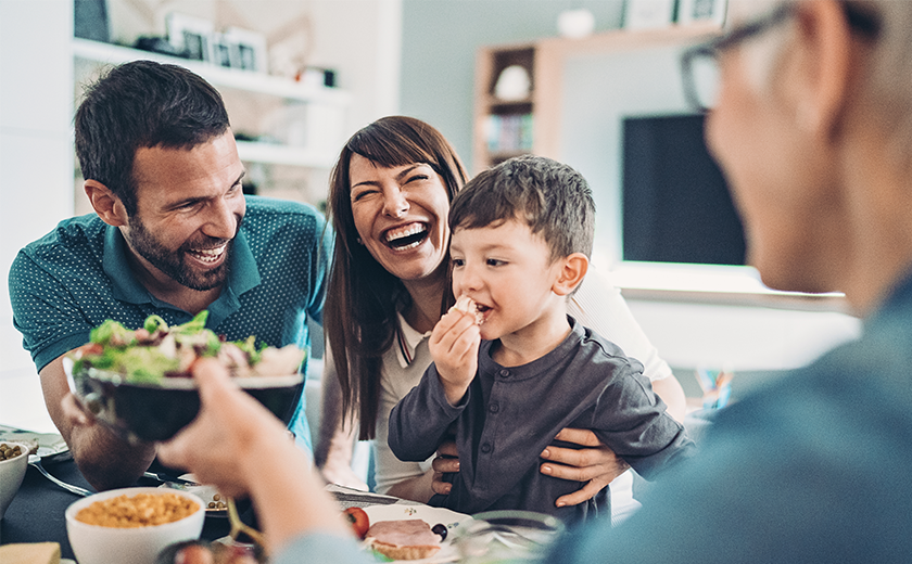 young family sitting at a table eating dinner