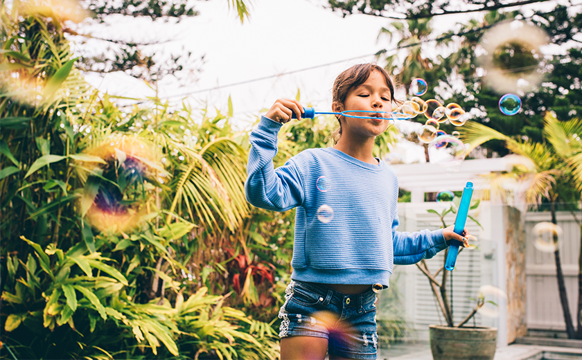 girl blowing bubbles near sunflowers