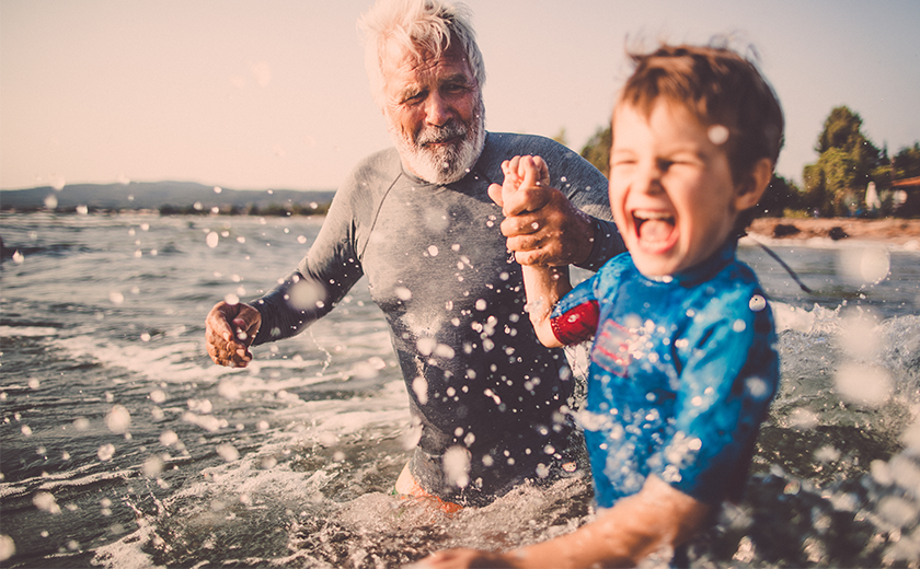 man with his grandchild at the beach