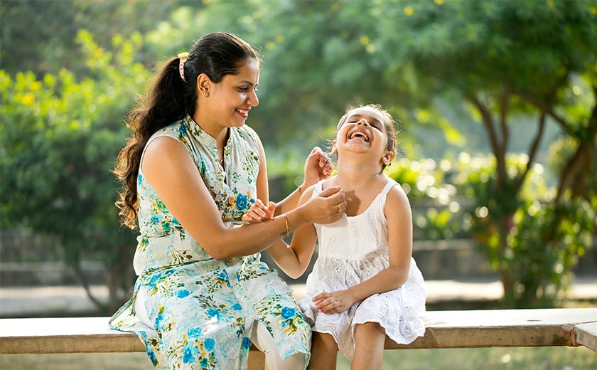 mother and daughter laughing on a bench seat