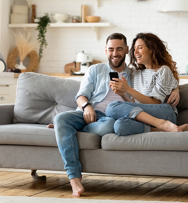 couple sitting on a couch looking at a smartphone