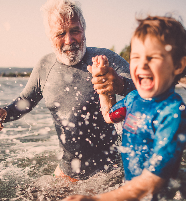 man with grandson playing at the beach