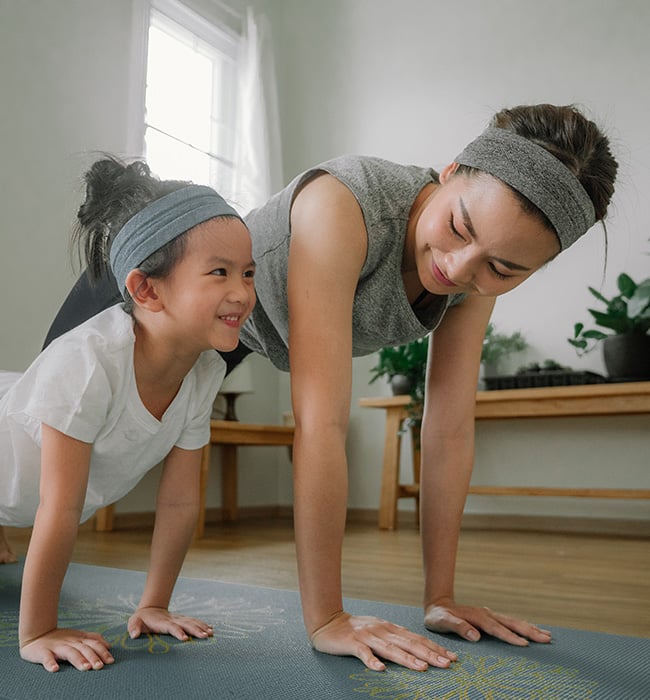 mother and daughter doing yoga inside