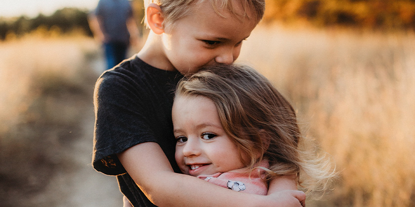 brother and sister hugging in a field